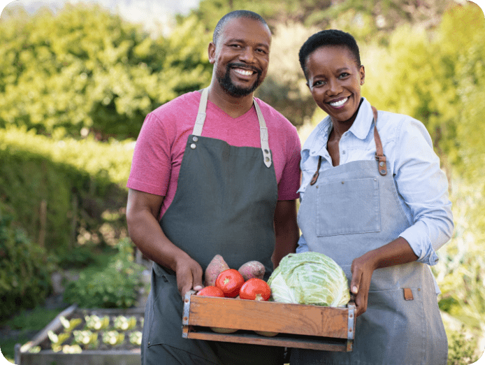 A couple holding a tray of fresh farm produce outdoors