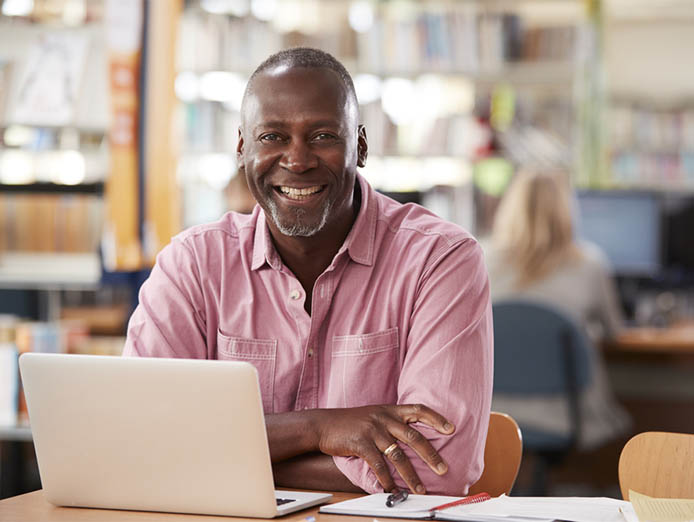 Portrait Of Mature Male Using Laptop In Library