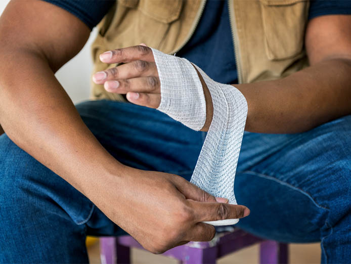 Well built man wrapping bandage on his wrist while seated